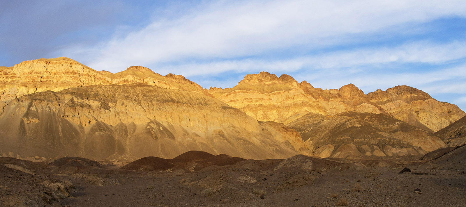 Mountains, tuff and debris from Miocene epoch volcanic activity along Artists Drive at sundown.  The red deposits contain oxidized iron-rich hematite.