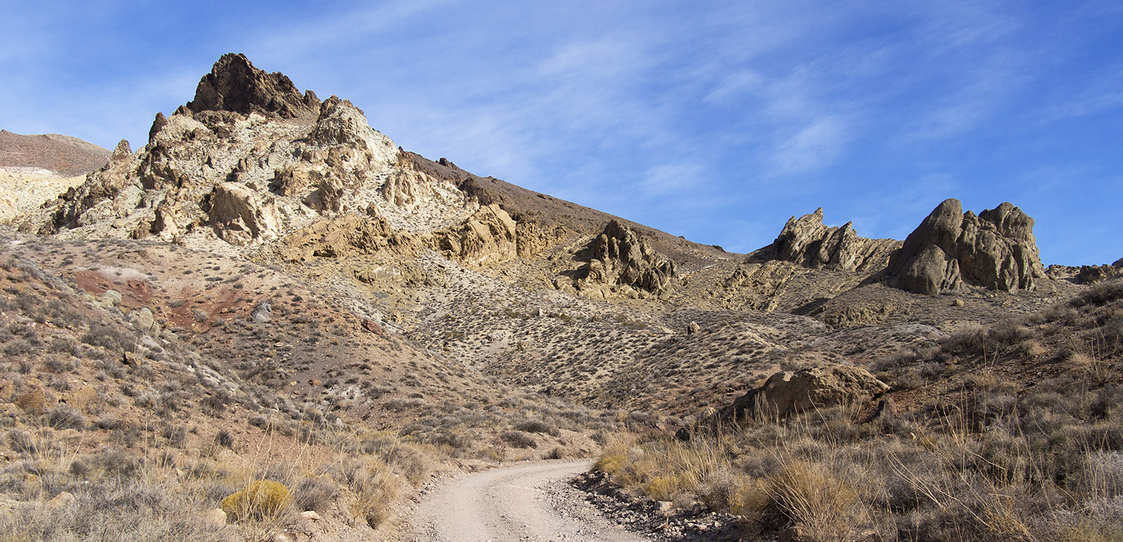Tilted and weathered strata of Cambrian Period Titus Canyon Formation topped by darker Tertiary Period volcanic rock on the way to Red Pass.