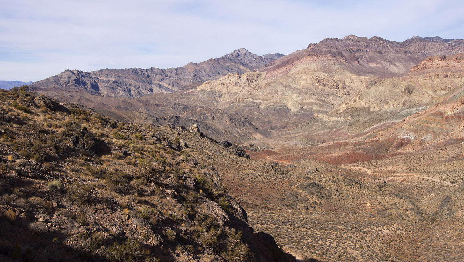 I'm standing on volcanic rock at the top of Red Pass looking Northwest into the upper part of Titus Canyon which was named after a young gold prospector (Morris Titus) who died in the canyon in 1905 from heat and dehydration after leaving behind a note that said he was looking for a spring.  Alternating dark and light strata of Bonanza King Formation are in the distance to the left.