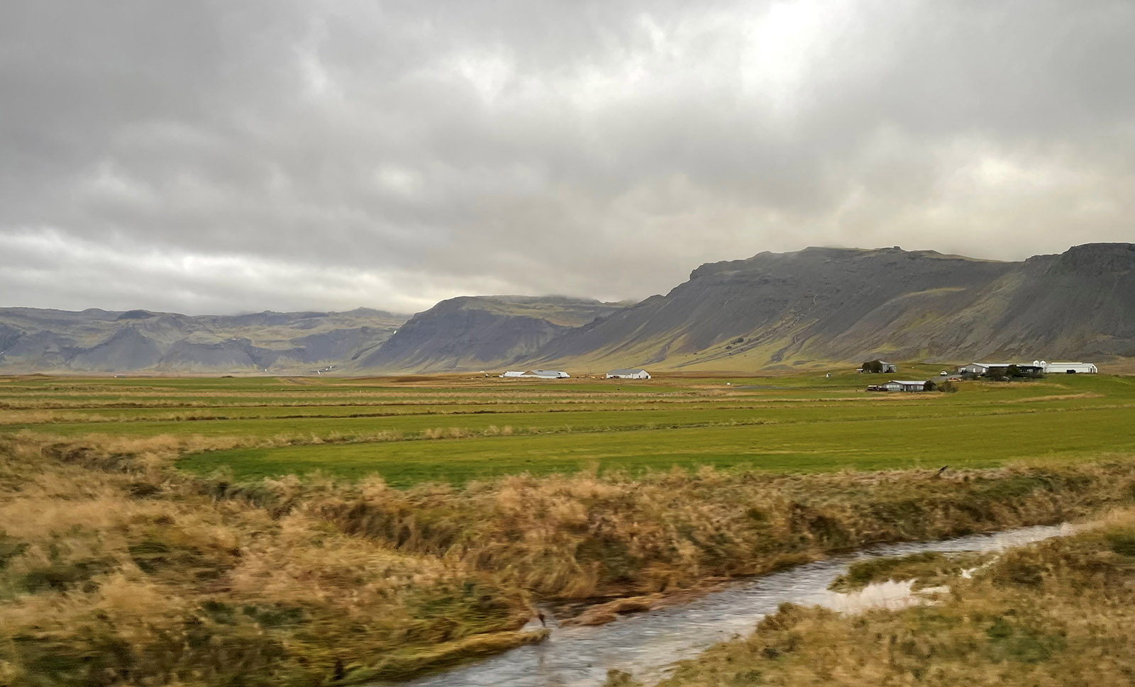 The view from highway 54 driving up the south edge of the Snæfellsnes Peninsula shows flat coastal plains with farms and pasture for sheep, cattle and horses. There are lava flow cliffs on the north edge of the plain.  Many of the cliffs are from tertiary lava flows more than 3.1 million years old.