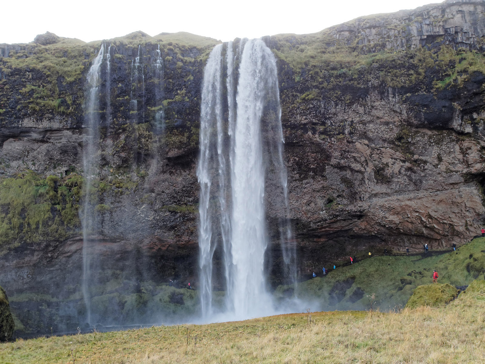 Seljalandsfoss is a 60m waterfall of the Seljalandsá River over a coastal cliff which formed at the edge of the Atlantic Ocean when water levels were significantly higher.  The cliff has at least three stratified layers.  Hamragarðahraun lava (basalt flow from around 940 CE) is at the clifftop, tillite (compressed unsorted sediments of glacial sediment from the terminal moraine) is in the middle, and hyaloclastite formed by subglacial eruption and rapid cooling of lava is at the bottom.