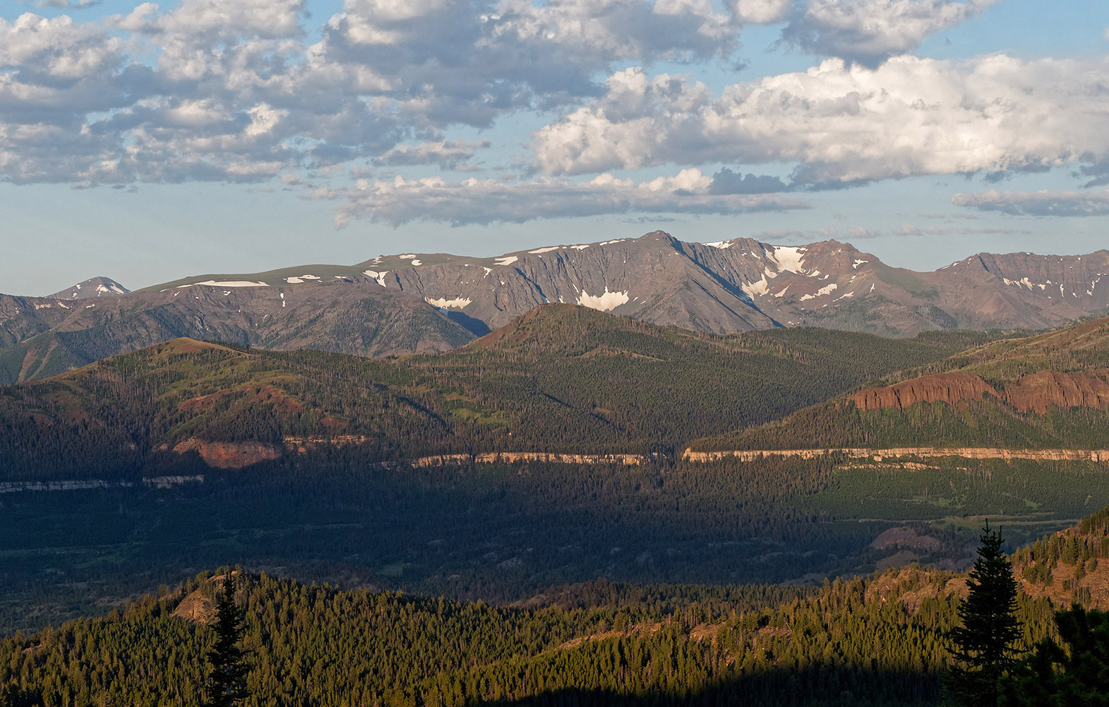Hurricane Mesa and other volcanic-origin mountains in the foreground in the Absaroka mountains lie above the lighter band of Pilgrim Formation limestone.